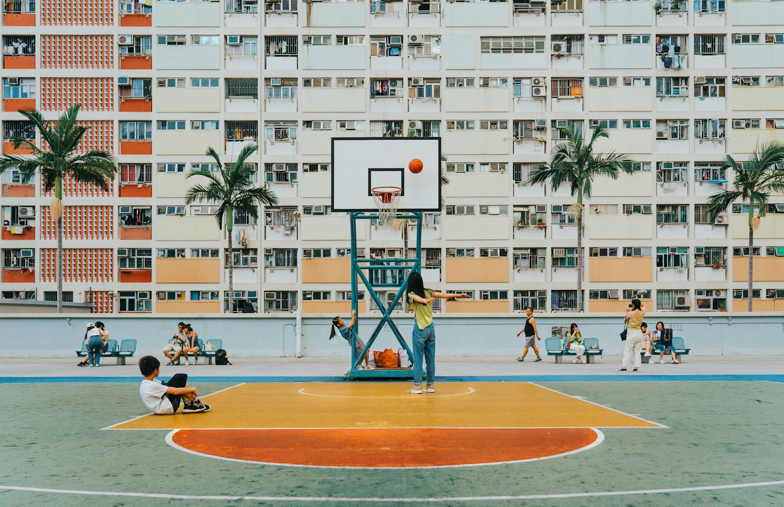 People play basketball in a colorful, urban setting.